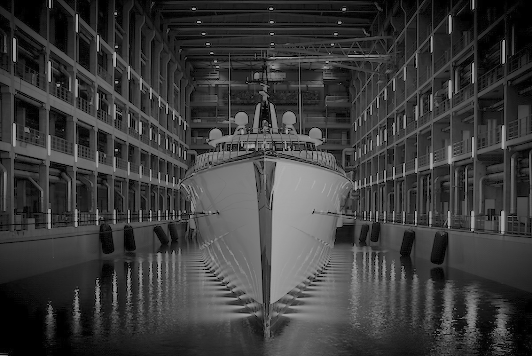 Superyacht in dry dock at the shipyard, illuminated by overhead lights